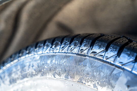 Wet car tire tread close up with water drops and rim