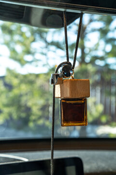 Hanging car air freshener bottle with wood cap in sunlight