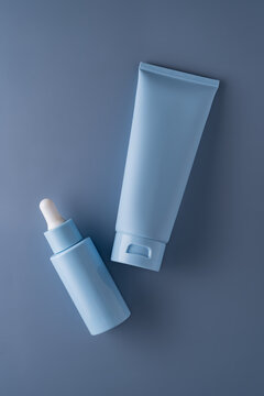 Minimal cosmetic serum bottle and cream tube on grey background