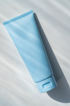 Minimal blue cosmetic cream tube packaging on light background