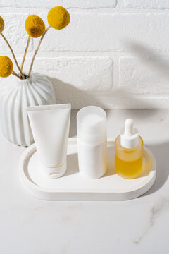 Minimal white skincare cosmetics set with serum on tray
