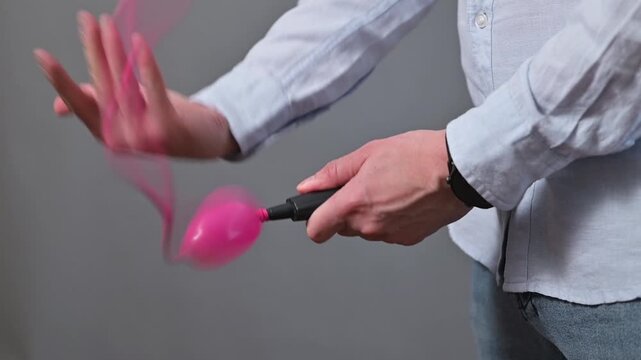 Close-up of an unrecognizable person trying unsuccessfully to inflate a balloon