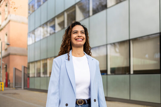 Confident businesswoman smiling outside modern office building