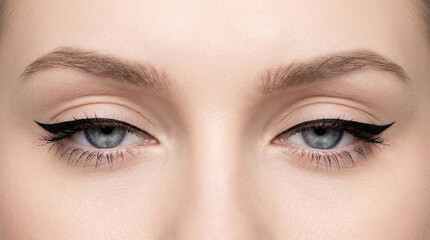Fototapeta premium Extreme close-up of blue woman eyes with sharp black winged eyeliner makeup.