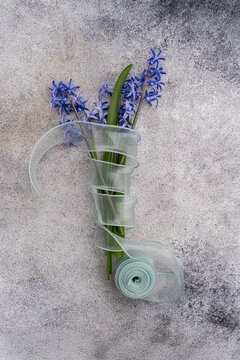Blue hyacinth bouquet wrapped in ribbon on stone surface