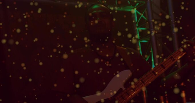 Vertical video: Male bassist emerging from shadow onstage, particles revealing white bass for music