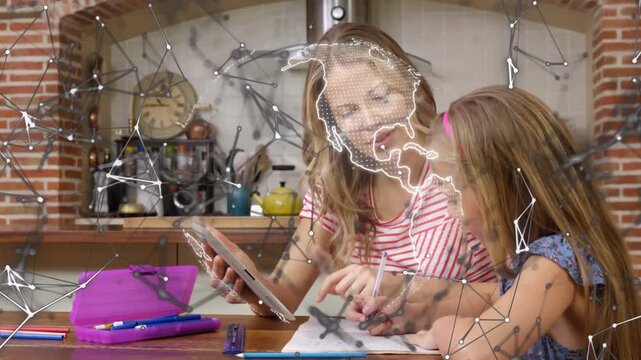 Mom guiding daughter learning at table, tapping tablet bringing pulsing globe over workbook