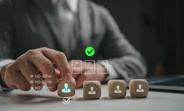 Businessman choosing wooden cube with blue people icon and check mark. Concept of human resources, recruitment, talent acquisition, career development, leadership, and professional job selection.
