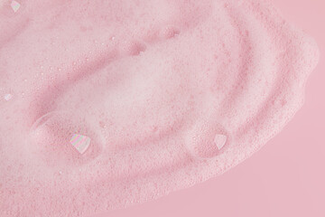 Fototapeta premium Whipped soap dense foam with bubbles on pink background . Cosmetic background. Copy of the space. Layout for the presentation of a spa product.