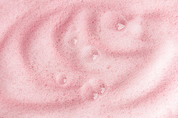 Obraz premium Delicate fluffy soap waves of foam with transparent bubbles on a pink background. A model of a cosmetic product for body skin care. detergent product.