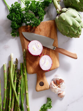 Fresh vegetables on marble countertop with knife and board