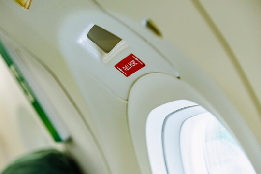 Plane cabin closeup with window and emergency exit latch