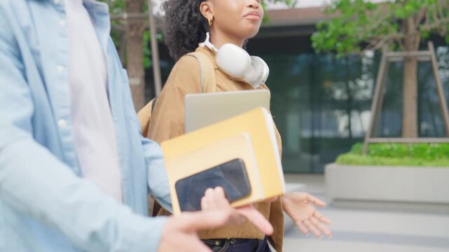 Close up of male and female students walking together on campus outdoors. 