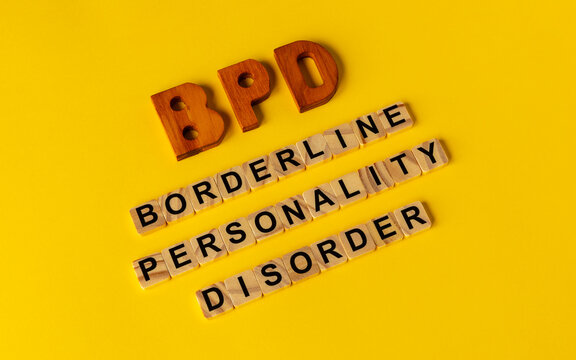 BPD abbreviation on wooden letters and its individual words: Borderline Personality Disorder, spelled out with wooden letter tiles on a yellow background.