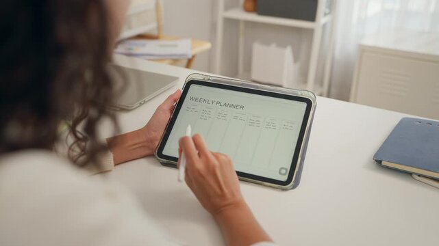Young Hispanic woman making a planner while sitting at a table at home. 