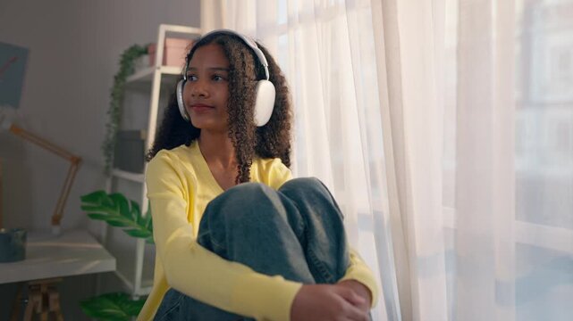 African American teenage girl wearing headphones and nodding head to the beat. 