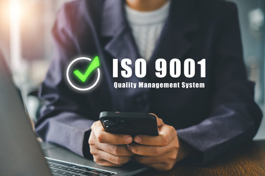 Close-up of a business professional using a smartphone with ISO 9001 quality management system concept in a modern office.