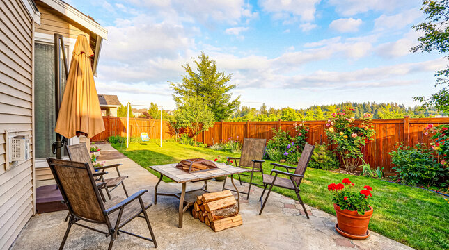 Cozy residential backyard patio with fire pit, outdoor furniture, and large umbrella for comfortable outdoor living.
