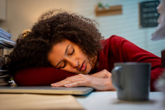 Exhausted young Latina woman overworking late at night in house. 
