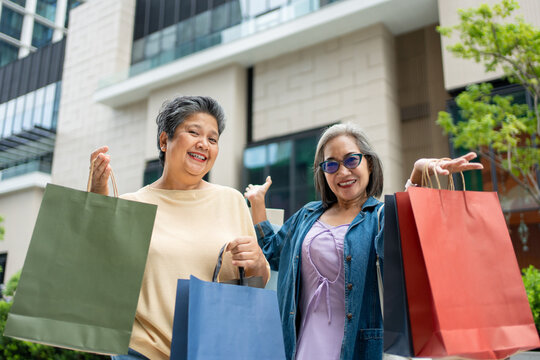 Portrait of Two Asian senior women standing outdoors with shopping bags. 