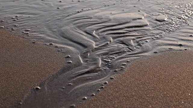 wet sand on beach with wave patterns and bubbles
