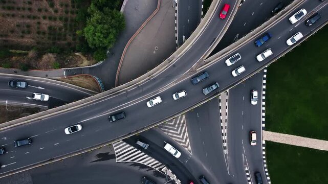 Aerial view of highway curve showing steady vehicle flow across elevated overpass filmed by drone from above in Tbilisi. Georgian logistics and commuter routes highlighted with concrete infrastructure