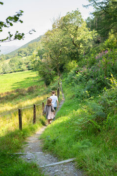 Two children walking along countryside path surrounded by greenery