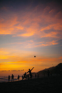 people playing football the beach during the sunset