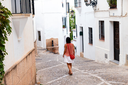 Woman walking down narrow white street in Spanish town
