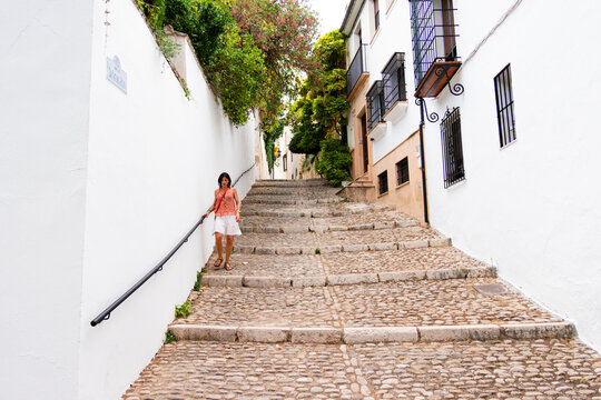 Woman walking down narrow white street in Spanish town