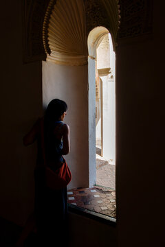 Woman looking through arched window in historic interior