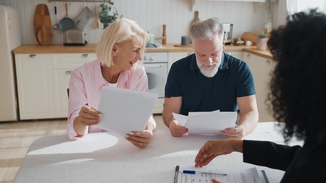 Aged people consulting with professional lawyer, man and woman reading contract. Senior spouses viewing agreements with real estate agency, examining conditions, rights and obligations of parties
