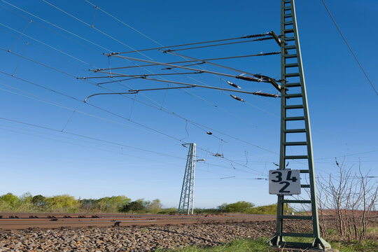 Railway overhead power lines and catenary system under a clear blue sky, showcasing modern rail infrastructure.