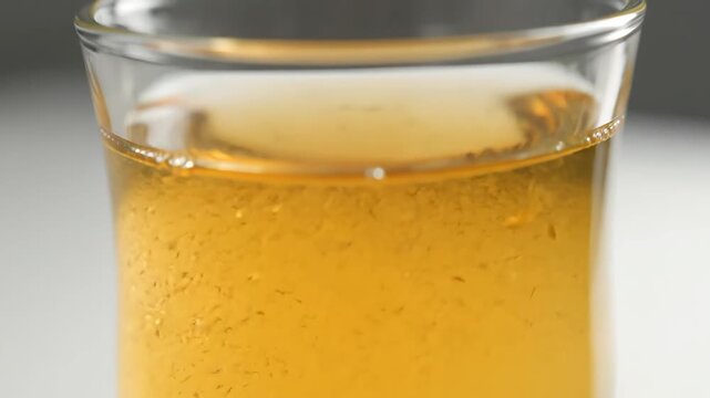 Macro close-up of golden beer pouring into a glass, showing intense carbonation, rising bubbles, and frothy white foam head for refreshing beverage detail