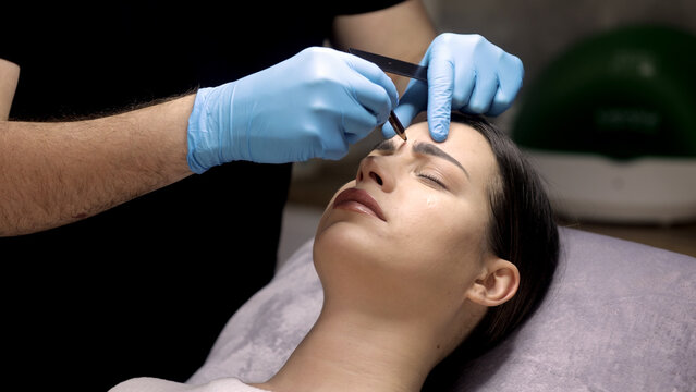 Cosmetologist in medical gloves marking injection zones on woman&rsquo;s face. Anti-aging concept.

