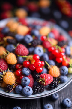 Close perspective of colorful berry mix in plate, natural light. Fresh organic summer fruits, healthy antioxidant concept