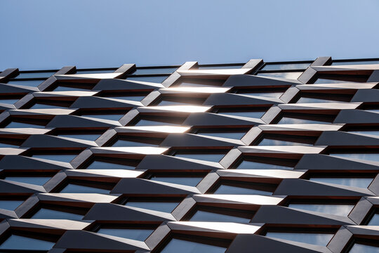 Modern metal facade in abstract architecture with geometric pattern texture repetition and sky creating a clean contemporary detail
