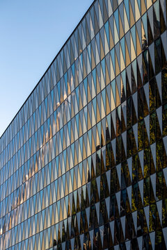 Modern glass facade architecture with windows and reflection forming a geometric abstract pattern on a highrise building in a clean urban view
