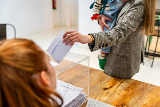 Woman holding child casting vote in ballot box