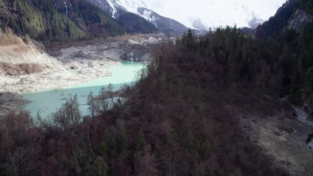 Drone view of Zhuxi glacier in Bomi County, Nyingchi, Tibet, China. High angle view of beautiful green glacial barrier lake among forest and gray rock, 4k real time footage b roll shot, travel concept