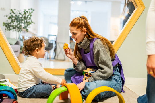 Daycare worker teaching toddler playing with toys