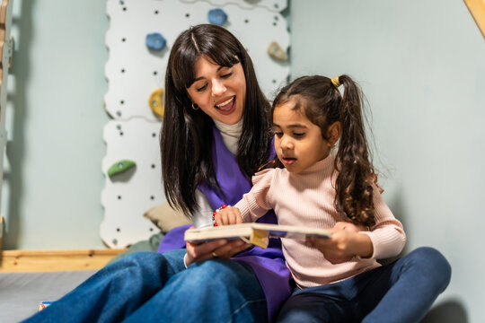 Daycare teacher reading book with diverse child