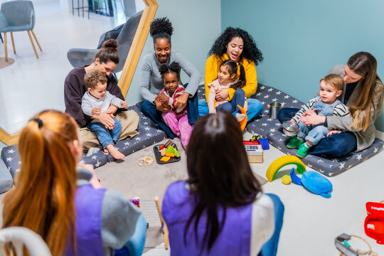Diverse group of mothers and children creating music in daycare