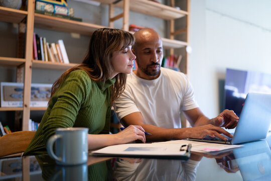 Couple signing agreement together at home with laptop and documents