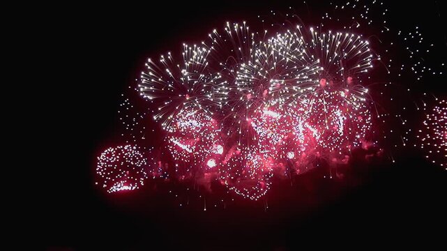 A mesmerizing display unfolds as bursts of ruby light illuminate the black canvas of night.