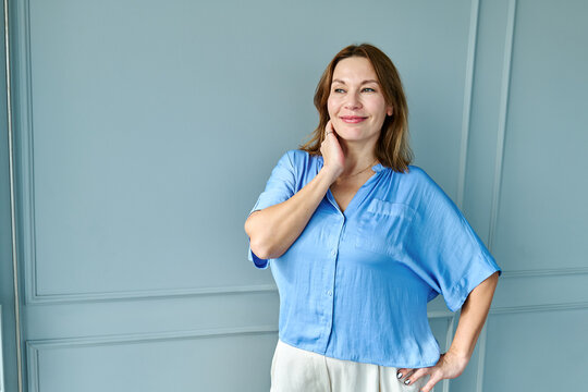 Smiling confident woman in blue shirt relaxing indoors