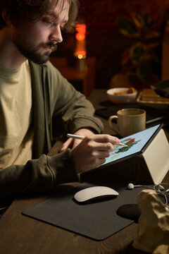 Freelancer creating digital art on graphics tablet in home office