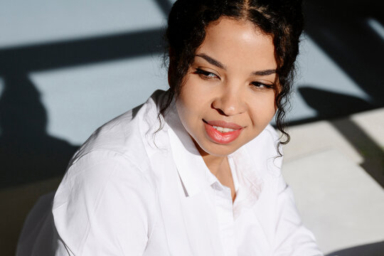 Portrarit of smiling woman with curly hair in bright sunlight