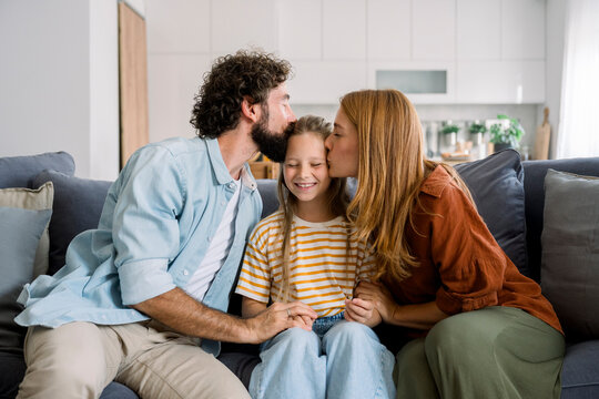 Family hugging and kissing child in living room filled with happiness