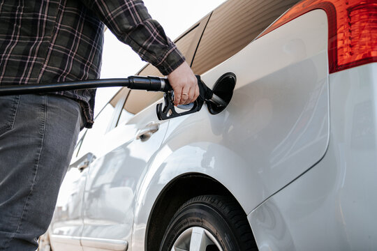 Refilling a white car with diesel at a gas station